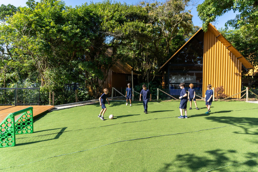 Students playing soccer at Theorema Bilingual School green campus in Balneário Piçarras, a bilingual education environment focused on active learning, sports and child development.