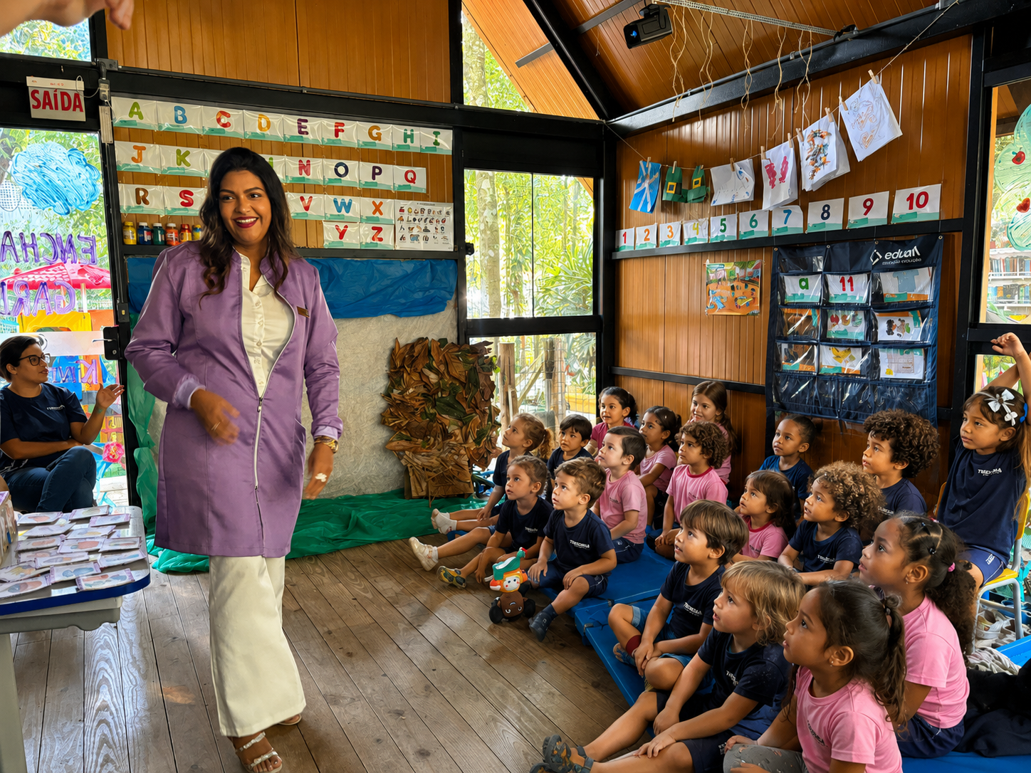 Professora realizando atividade pedagógica com alunos da educação infantil na Theorema Bilingual School em Balneário Piçarras, promovendo aprendizagem lúdica, desenvolvimento infantil e ensino bilíngue em ambiente acolhedor.